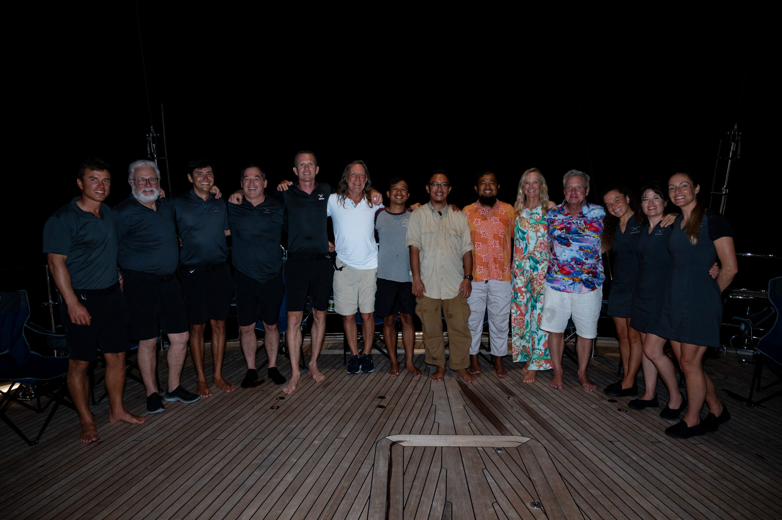 Group Photo with scientists Tiger Shark swimming in clear blue water with sunbeams coming from above