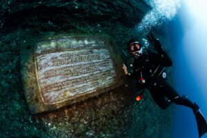 A scuba diver poses next to the Plaque of the Revillagigedo Marine Park